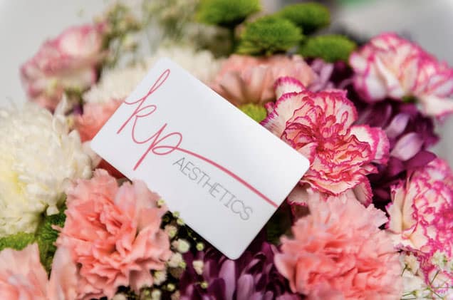 KP Aesthetics gift card on a bouquet of pink flowers.