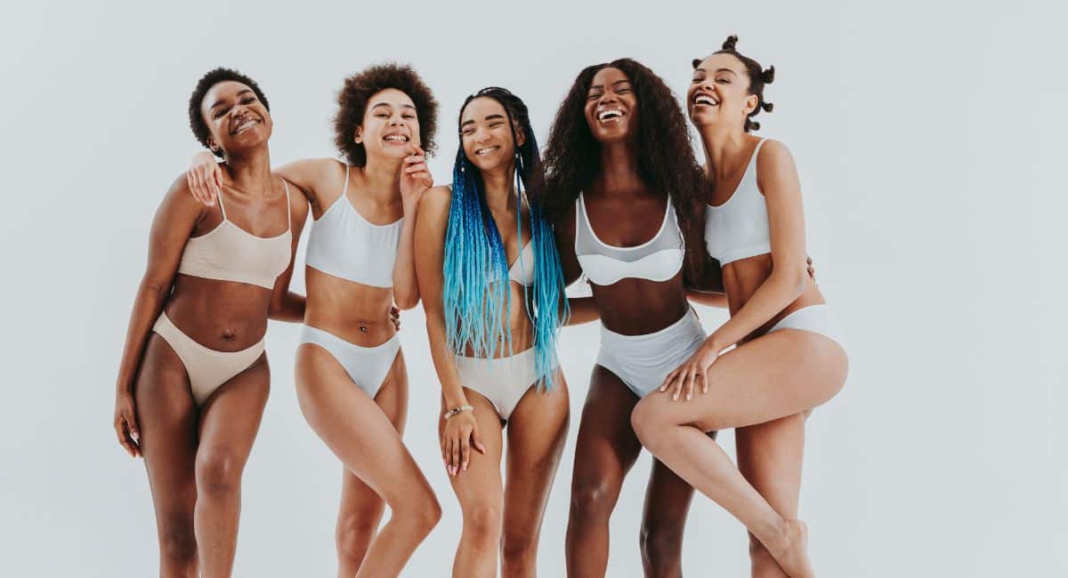 group of women smiling while showing their various skin tones in tight waist suits